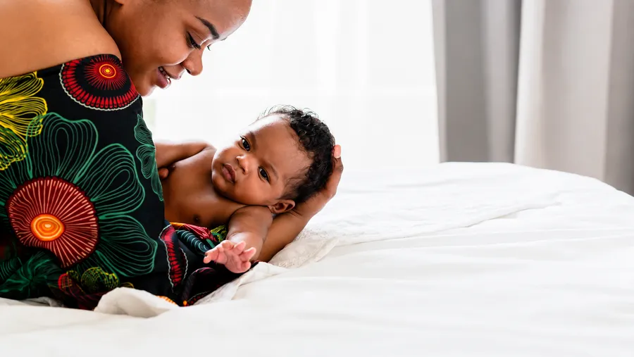 A mother supported by DLT Foundation's welfare programs cradling her baby